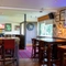 Interior dining area of a pub with a TV, a gambling machine and a dartboard.