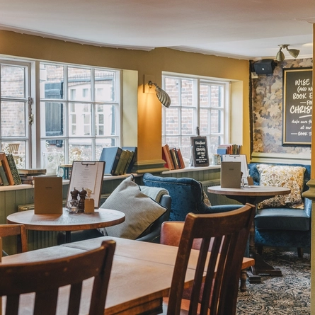 An interior restaurant seating area at The Inn On The Green, with upholstered chairs with cushions, and books on the window sills.