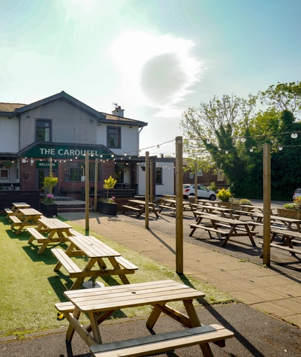 Exterior facade and beer garden of a pub with a seating area.