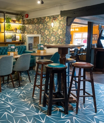 An interior restaurant seating area at The Royal Oak in Bishops Cleeve; with an upholstered booth seat against one wall, a TV on the wall above it, and a gaming machine.