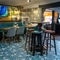 An interior restaurant seating area at The Royal Oak in Bishops Cleeve; with an upholstered booth seat against one wall, a TV on the wall above it, and a gaming machine.