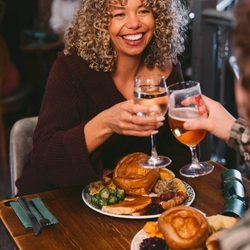 A group of people seated at a festive decorated table  with plated meals and drinks in front of them.