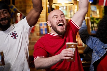 A mixed group of people holding a drink and cheering.