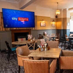 An interior restaurant seating area at the Tamar, with an upholstered booth seat, a fireplace, and a TV on the wall above it.