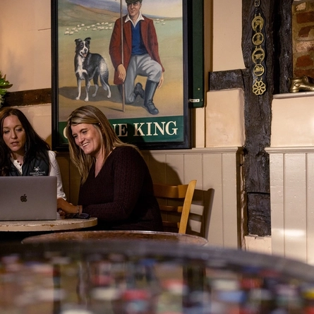 Three women sat around a table looking at a laptop