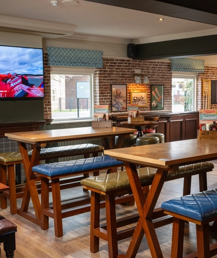 The interior restaurant seating area of The Longship, with a fireplace, a TV on the wall, a dartboard, and a pool table.