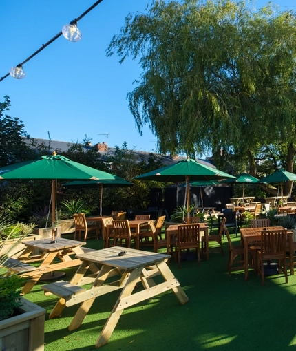 The exterior beer garden seating area at The Talbot Inn in Mansfield, with wooden picnic tables and shade umbrellas.