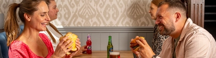 An image of 4 people enjoying burgers and drinks within the interior restaurant and seating area at a Hungry Horse venue.