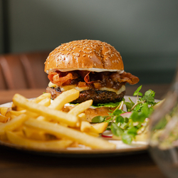 An advertising image featuring a Game Wild Boar Burger dish sat on a table from the Game Festive Menu at Chef & Brewer venues.