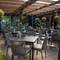 The paved, exterior beer garden seating area at The Ship in Bedford; with a large wooden pergola sheltering the tables and chairs, and flower baskets and string lights hanging from the dark wooden beams.