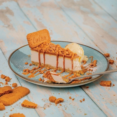 A slice of Biscoff cheesecake served on a plate with a spoon.