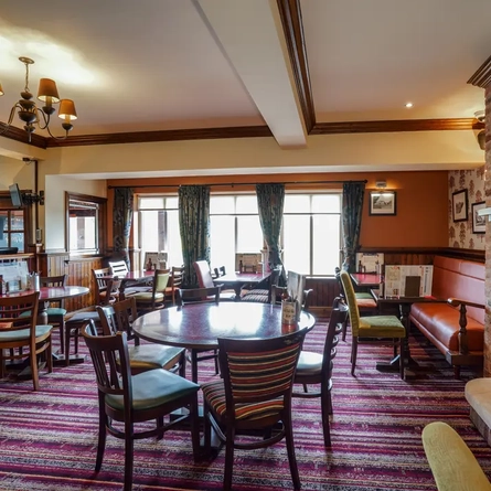Internal dining area of a pub with a fireplace.