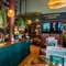 The wood panelled bar and interior restaurant seating area of The Fountains Abbey, with metal tables, stool seats, a TV on the wall, and plants hanging above the bar.