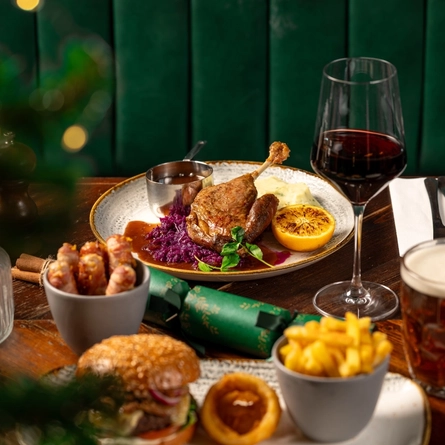 A plated roast duck dish on a festive decorated wooden table.