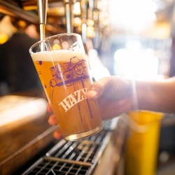 A close up image of a pint of Hazy Day being poured behind the interior bar at a Community Pubs With Food venue.