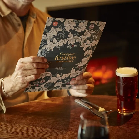 A person's hands holding a menu at a table.