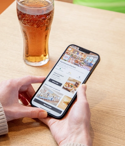 Hands holding a mobile phone displaying the Farmhouse Kitchen order screen.
