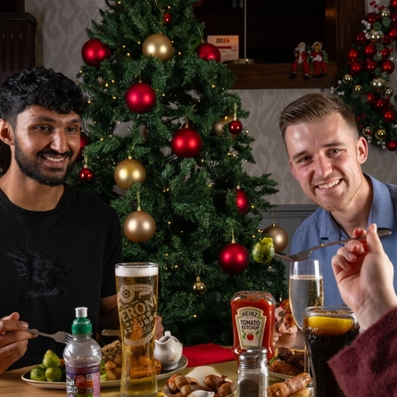 A group of people seated around a festive decorated table with plated meals in front of them.