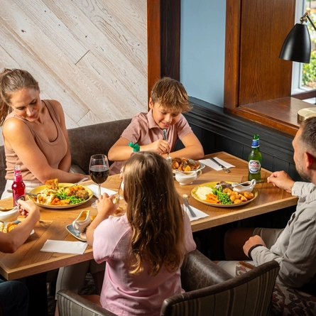 An image of a family enjoying a Sunday Roast and various drinks within the interior restaurant and seating area at a Hungry Horse venue.
