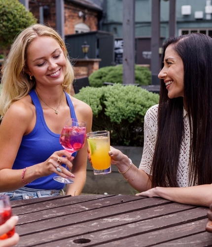 A mixed group of people enjoying cocktails in a beer garden.