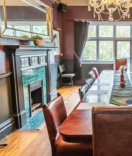 The interior of one of the function rooms with tiled fireplace and large table laid out with pens and paper at The Vine.