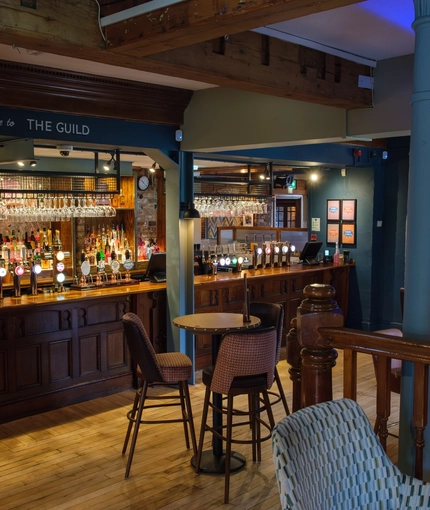 An image of the interior bar and restaurant seating area with TV and electronic pub games at The Guild.