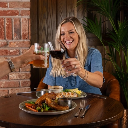 Two friends seated at the restaurant area in a Greene King Community Pubs with Food venue enjoying mains off the specials menu.