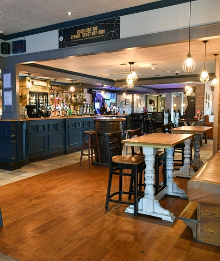 Interior dining area of a pub with a bar and a TV.