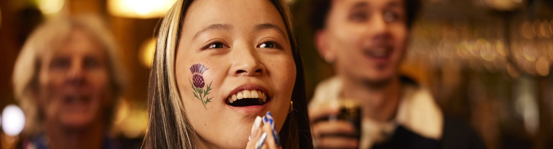 An image of a woman wearing a sport team shirt, watching a sporting event.