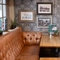 An interior restaurant seating area at The Woolpack Inn; with an upholstered booth seat, and framed artwork on the wall.