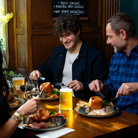 A group of friends seated in the restaurant and seating area of a Urban Social venue, enjoying Sunday roast dinners and drinks.