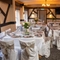 The function room at The Cherry Tree, set up for a wedding; with a TV on the wall, white tablecloths and seat covers, pink napkins, and vases of flowers on each table.