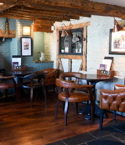 The restaurant area of The White Hart, with a fireplace amongst the tables.
