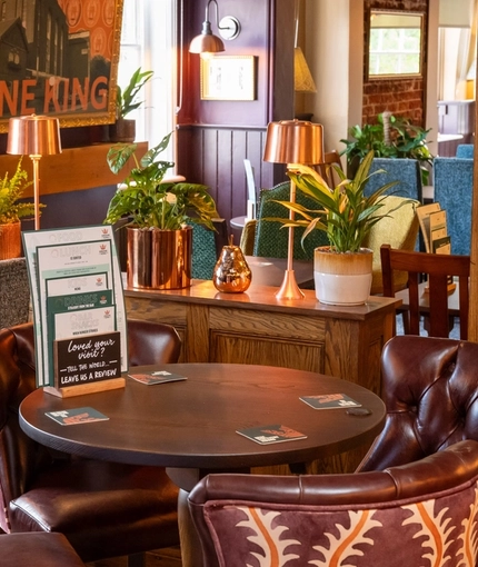 The interior restaurant seating area at The Fox in Bury St Edmunds, with a wood panelled column, and upholstered chairs.