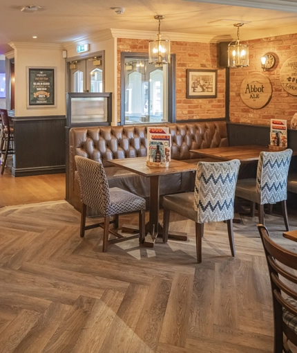 Interior dining area of a pub with a bar and a gambling machine.