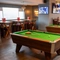 The interior games area at the Devonshire Arms, with two pool tables, TVs on the walls, and restaurant seating.