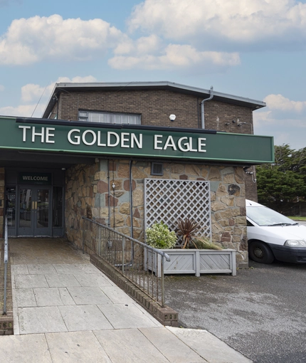 Exterior facade and car park of a pub.