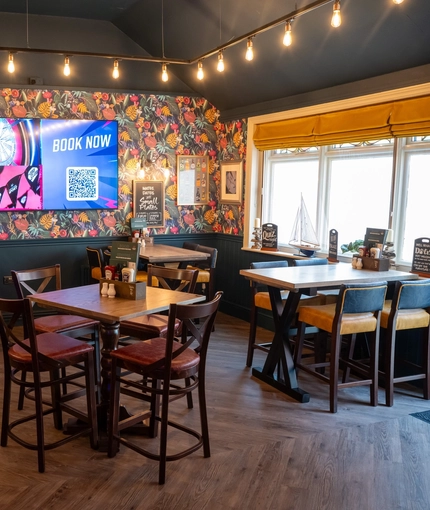 An interior restaurant seating area at The Grosvenor, with a pub gaming machine, and a TV on the wall.