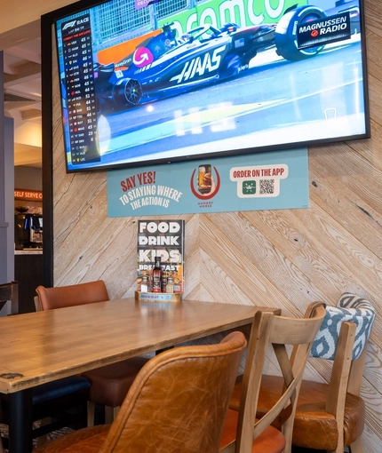 An interior restaurant seating area at The Weathervane, with upholstered booth seats, and a TV on the wall.