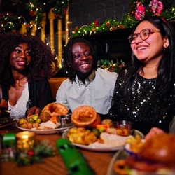 A group of people enjoying various main meals and drinks within the interior restaurant and seating area of Greene King Pub venue.