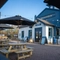 The exterior facade, signage, and beer garden seating area of The Kittoch, with wooden picnic tables, shade umbrellas, and string lights overhead.