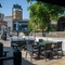 The exterior beer garden seating area of The Woolpack Inn; with wooden picnic tables, a TV, and a view of the surrounding buildings.