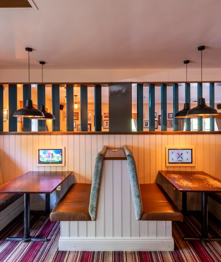 Interior dining area of a pub with a few TVs.