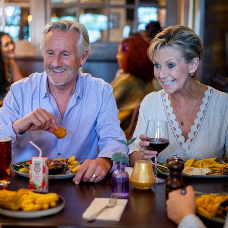 An image of a family enjoying various dishes and drinks within the interior restaurant seating area at a Community Pubs With Food venue.