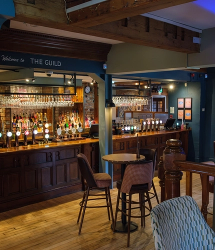 An image of the interior bar and restaurant seating area with TV and electronic pub games at The Guild.