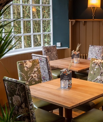 An interior restaurant seating area at The Fox & Hounds in Bursledon, with upholstered chairs and a brick fireplace.
