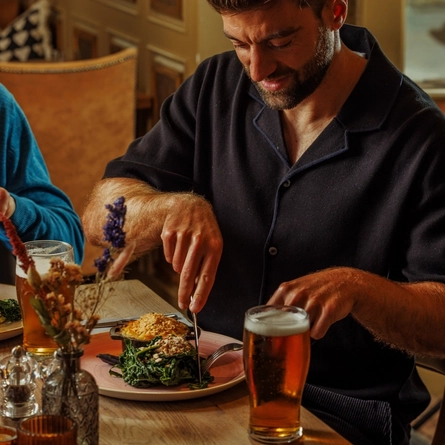 An image of 2 people enjoying Pie Choice Mains and drinks within the interior restaurant seating area at The Foundry Bell.