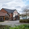 The exterior facade, signage, seating area, car park, and children's play area of The Parsonage in Leigh.
