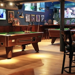 Interior dining area of a pub with a few TVs and pool tables.