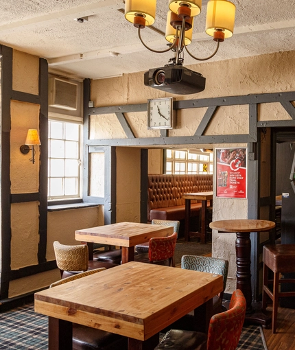 Interior dining area of a pub with a TV, a fireplace, a pool table and a gambling machine.